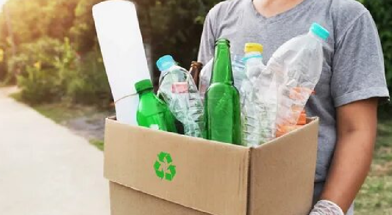 A person holding a recycling box filled with plastic and glass bottles for dry waste collection services in Bangalore by Urban Eco Recyclers