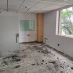 Corporate Office Waste Management – Best Practices An empty commercial office room showing concrete floors covered in dark dust, cable ties, and drywall trash right after furniture and partition dismantling.