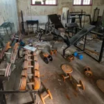 Gym and Fitness Center Dismantling Services in Bangalore Heavy metal dumbbell racks and loose iron weights undergoing material sorting for scrap buyback during a gym strip-out.