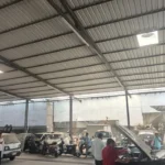 Automotive garage and warehouse structure with parked scrap vehicles undergoing site clearing and heavy metal salvage.