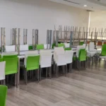 Corporate cafeteria tables and green chairs organized for bulk removal in a Bangalore office.