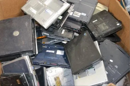 Stacked old laptop scrap shells awaiting dismantling by certified bulk computer buyers